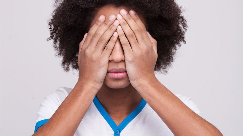 Girl with her hands covering her eyes, trying to resist the power of pornography