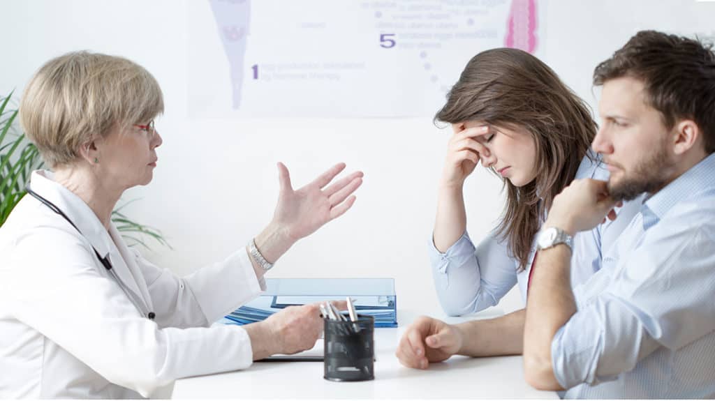 A docto in white offers a young couple healthy ways to grieve their pregnancy loss.