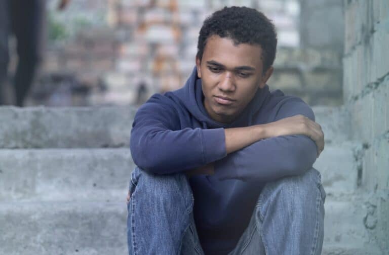 Contemplative teen boy sitting on steps