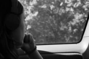 Solemn girl looking out car window. Black and white photo.