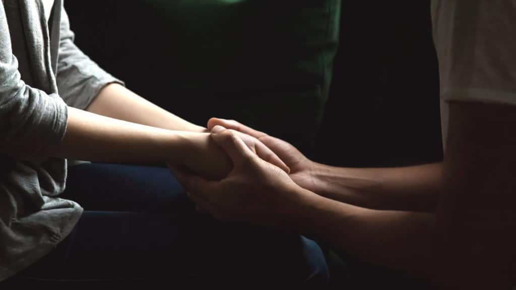 Close-up of husband and wife holding hands coping with miscarriage