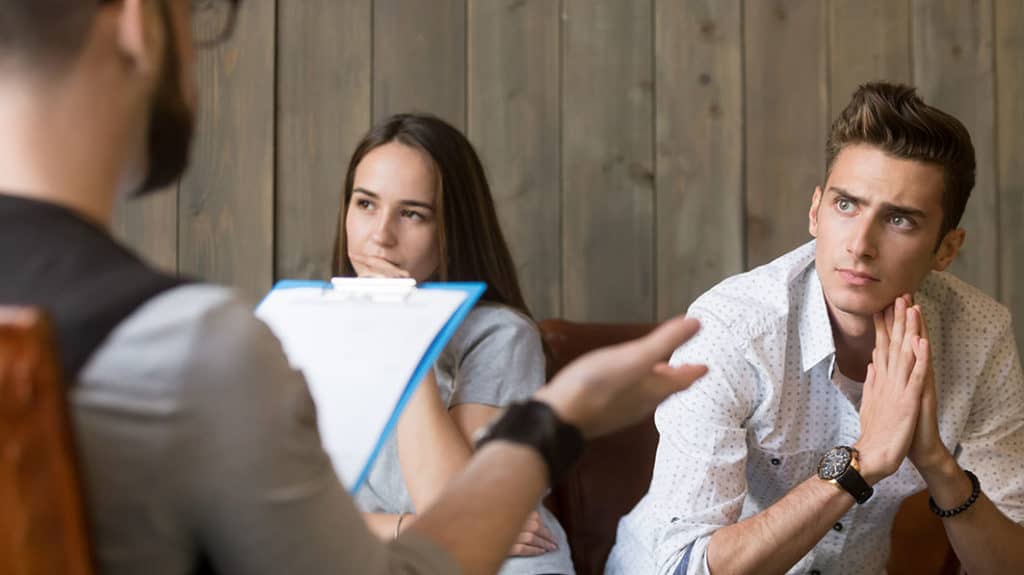 Counselor confronting husband in office as wife looks on