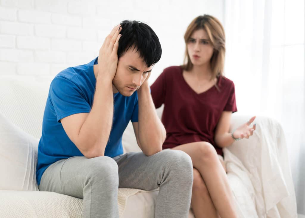 Husband-being-criticized-by-wife-sitting-on-couch