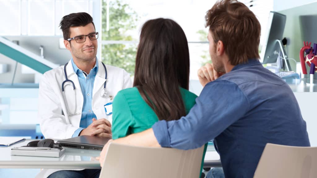 Husband-and-wife-talking-to-doctor-about-trying-to-get-pregnant