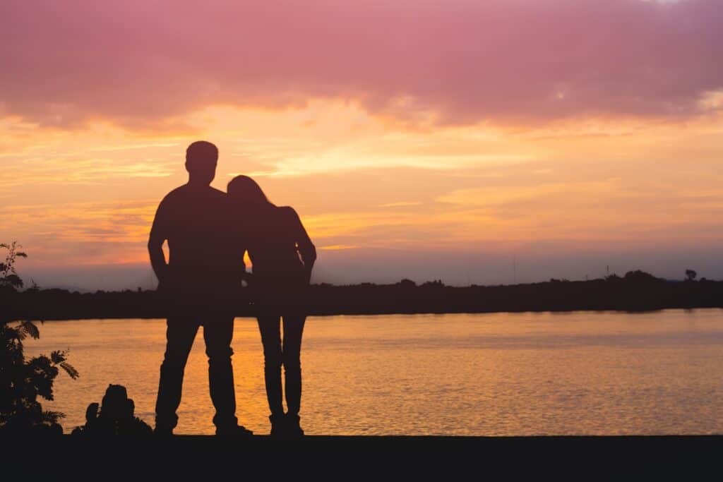 A woman restes her head on her husband's shoulders as they watch the sunset. Perseverance is the best weapon against depression.