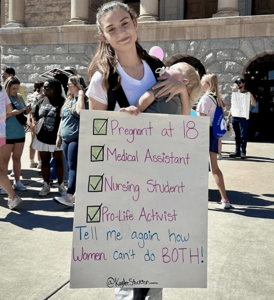 Image of woman at March for Life carrying a sign with mom quotes