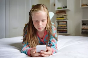 young girl texting her friend while laying on her bed