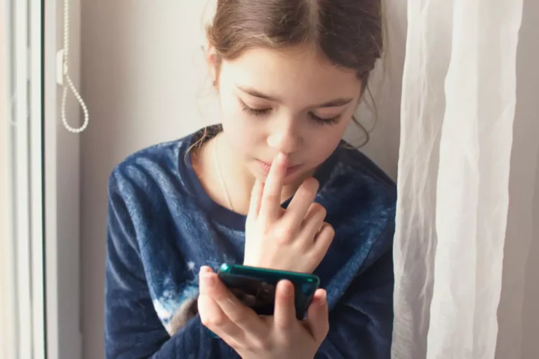 young girl holding a smart phone, distressed looking at social media