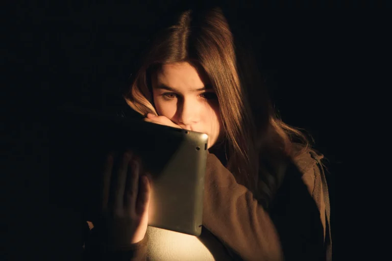 Witchcraft, teenage girl sitting in the dark reading about witchcraft on her tablet.